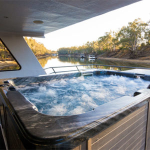 Hot tub on a houseboat with scenic river view.